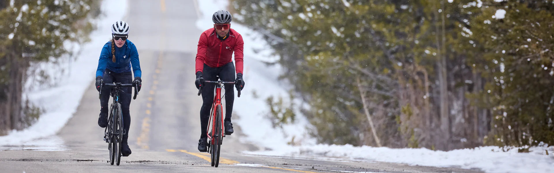 two cyclists on snowy road wearing winter cycling gear